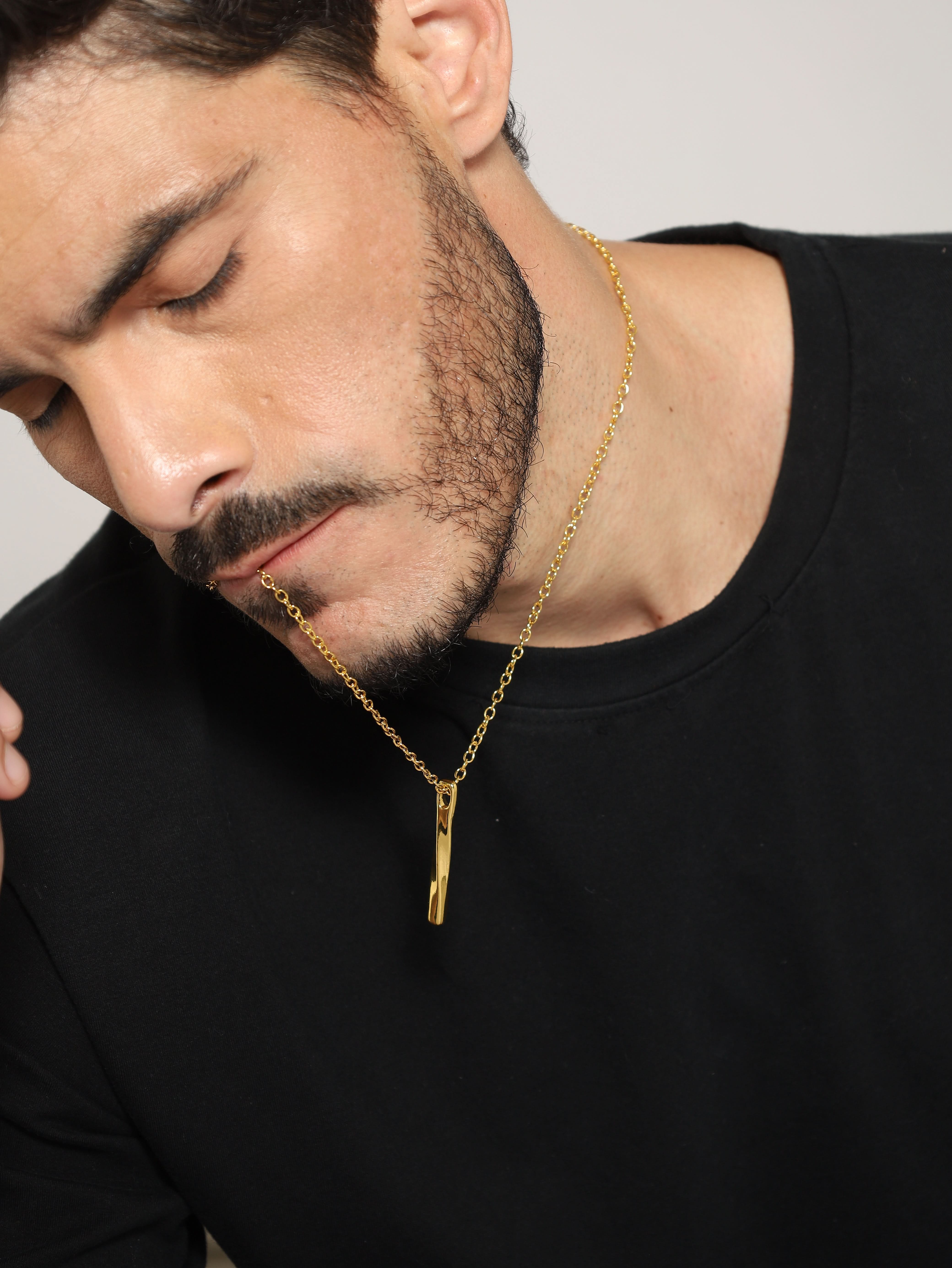 Model wearing Twisted Long Vertical Bar Pendant in gold — men's gold pendant styled on hand