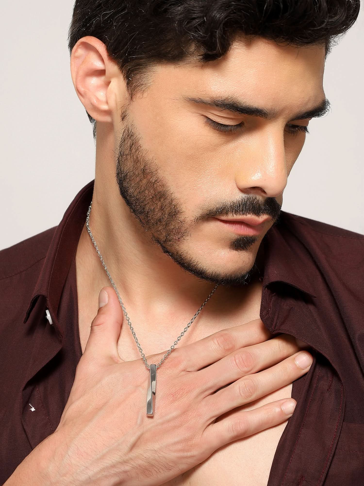 Model wearing Twisted Long Vertical Bar Pendant in silver — men's silver pendant styled on hand