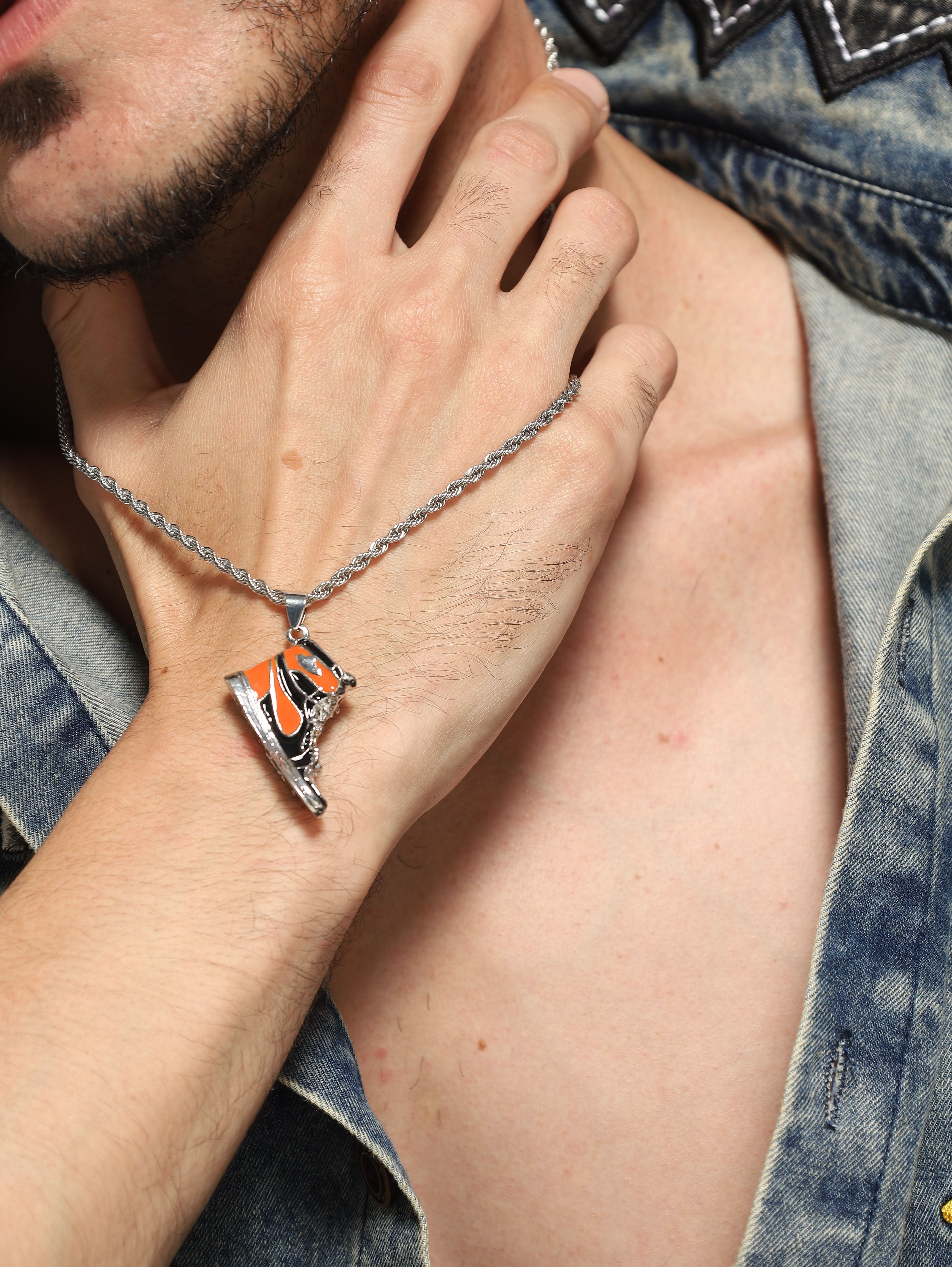 Model wearing Sneaker Pendant in orange — men's orange pendant styled on hand