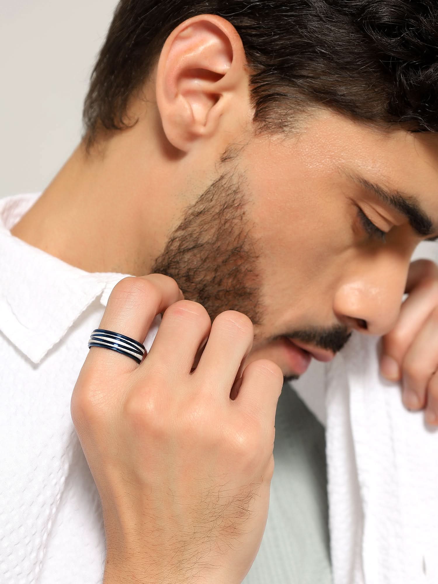 Model wearing Crossover Line Ring in blue — men's blue ring styled on hand