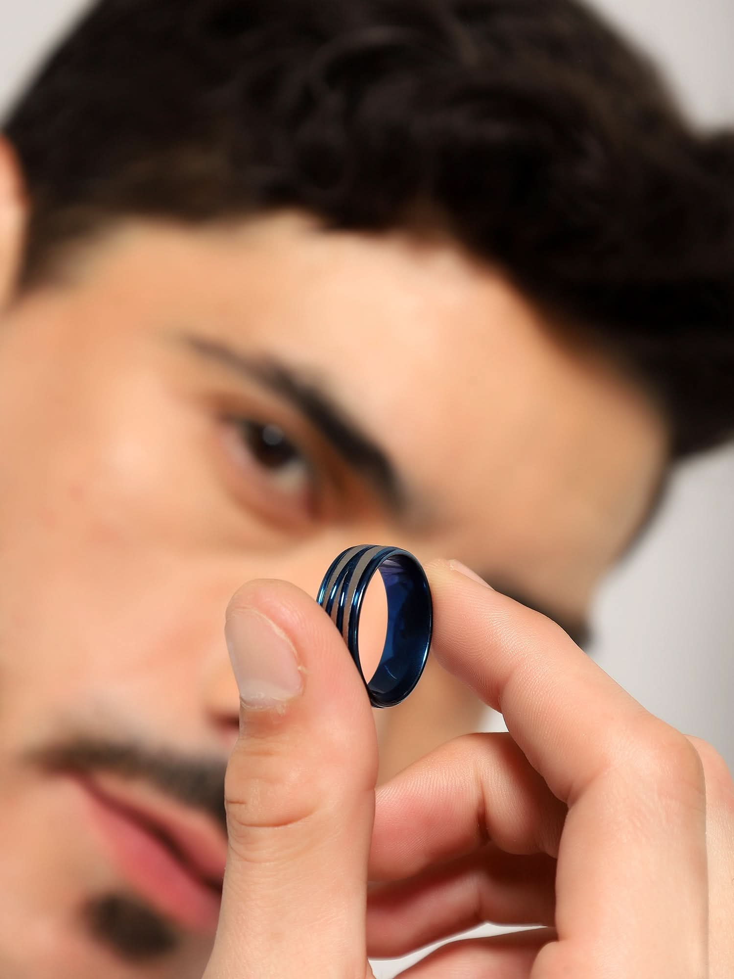 Model wearing Crossover Line Ring in blue — men's blue ring styled on hand