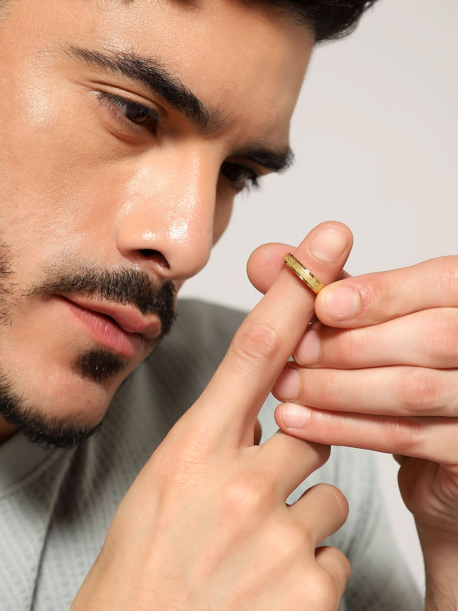 Model wearing Glitty Trose Embossed Ring in gold — men's gold ring styled on hand